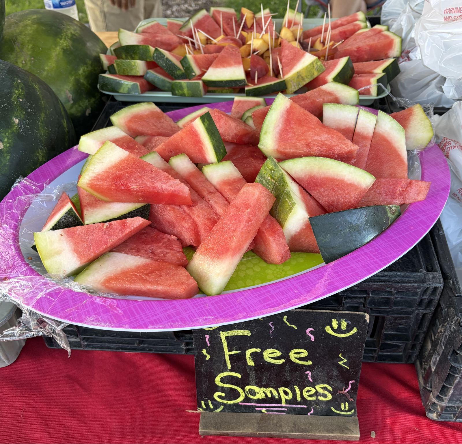 Watermelon cut into free samples on toothpicks beside a Free Samples sign